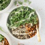 Chickpea grain bowl drizzled with tahini dressing with a gold spoon nestled in