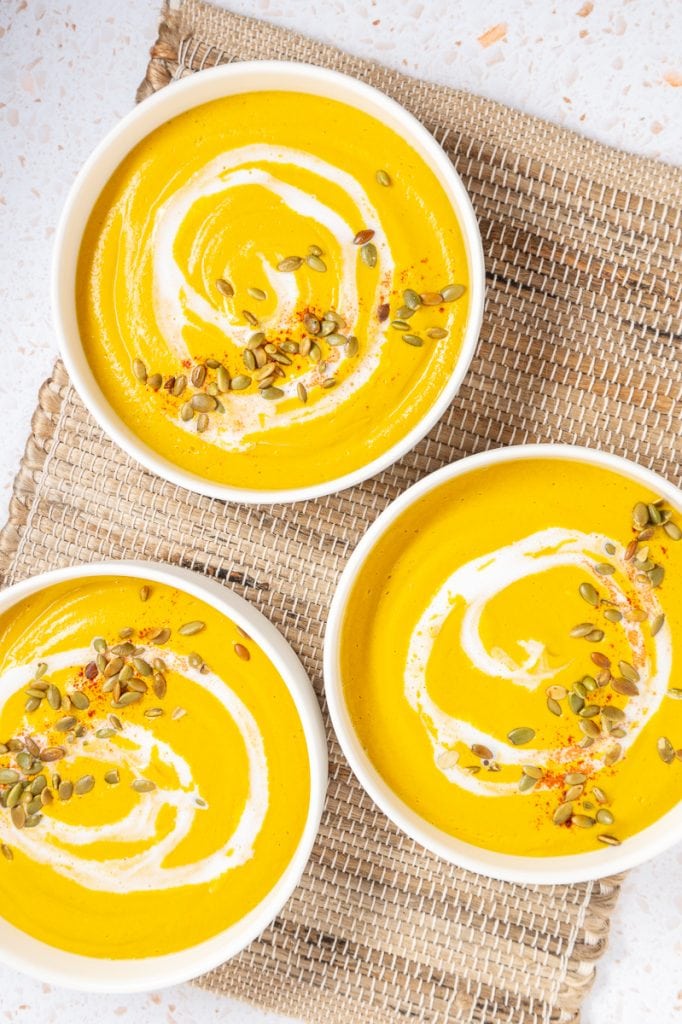 Three bowls of soup with toppings on a jute placement