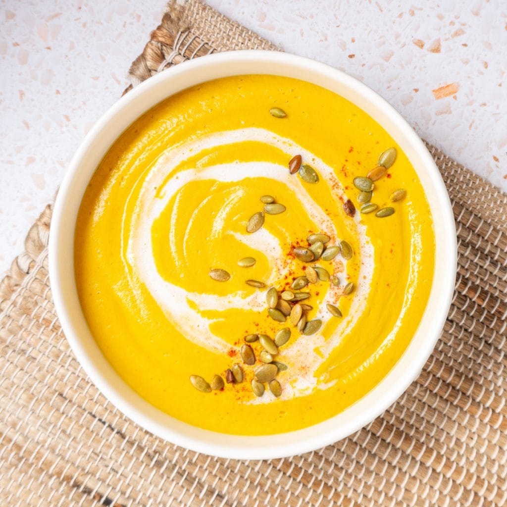 Bowl of Pumpkin Soup with pepitas and coconut milk on top