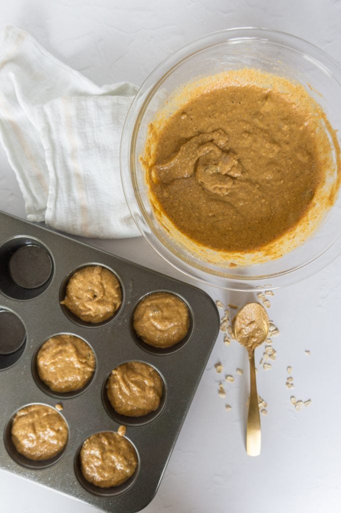 muffin pan, bowl of batter, and spoon for scooping batter into muffin pan
