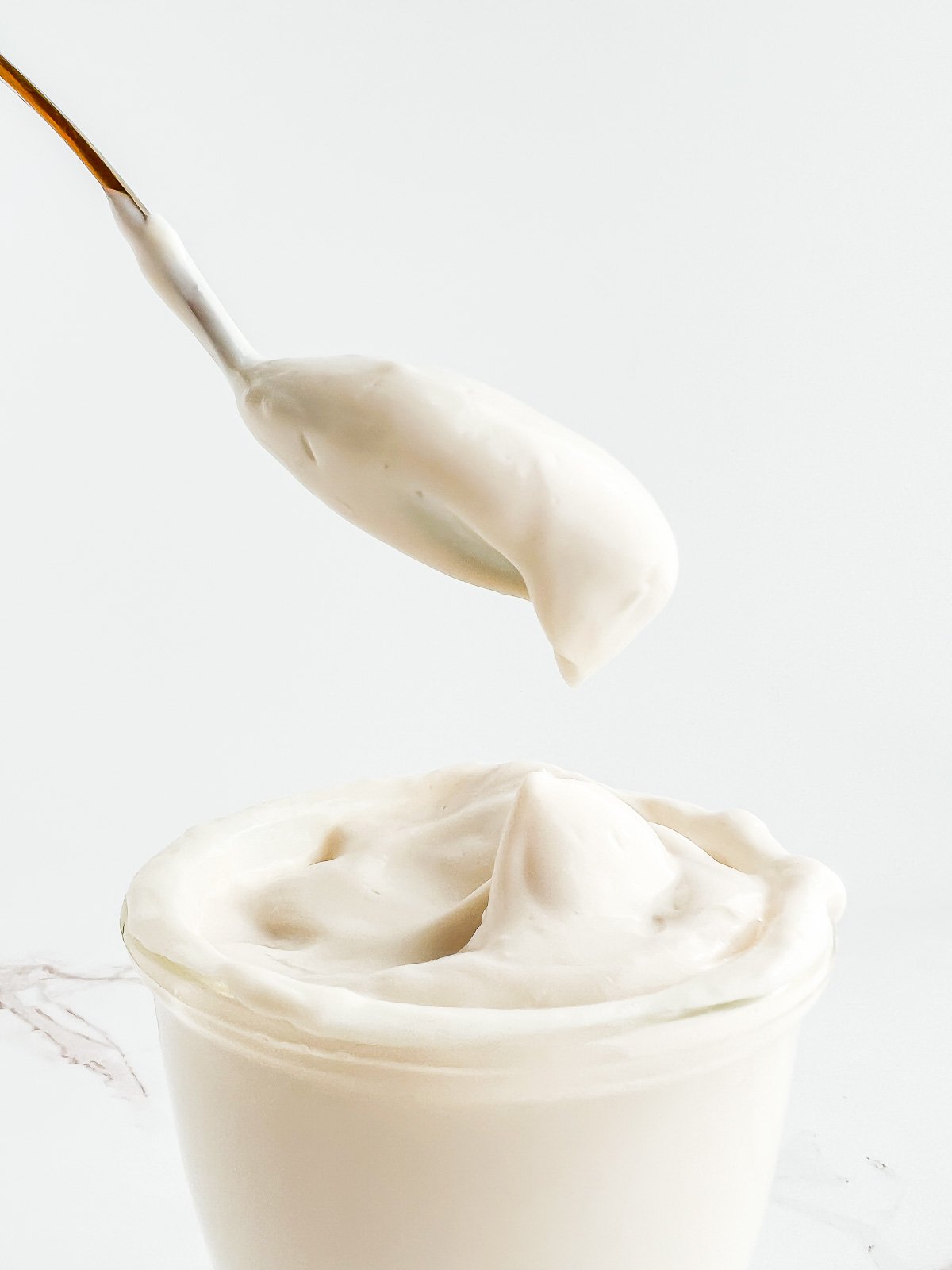spoonful of vegan sour cream being taken from a glass jar