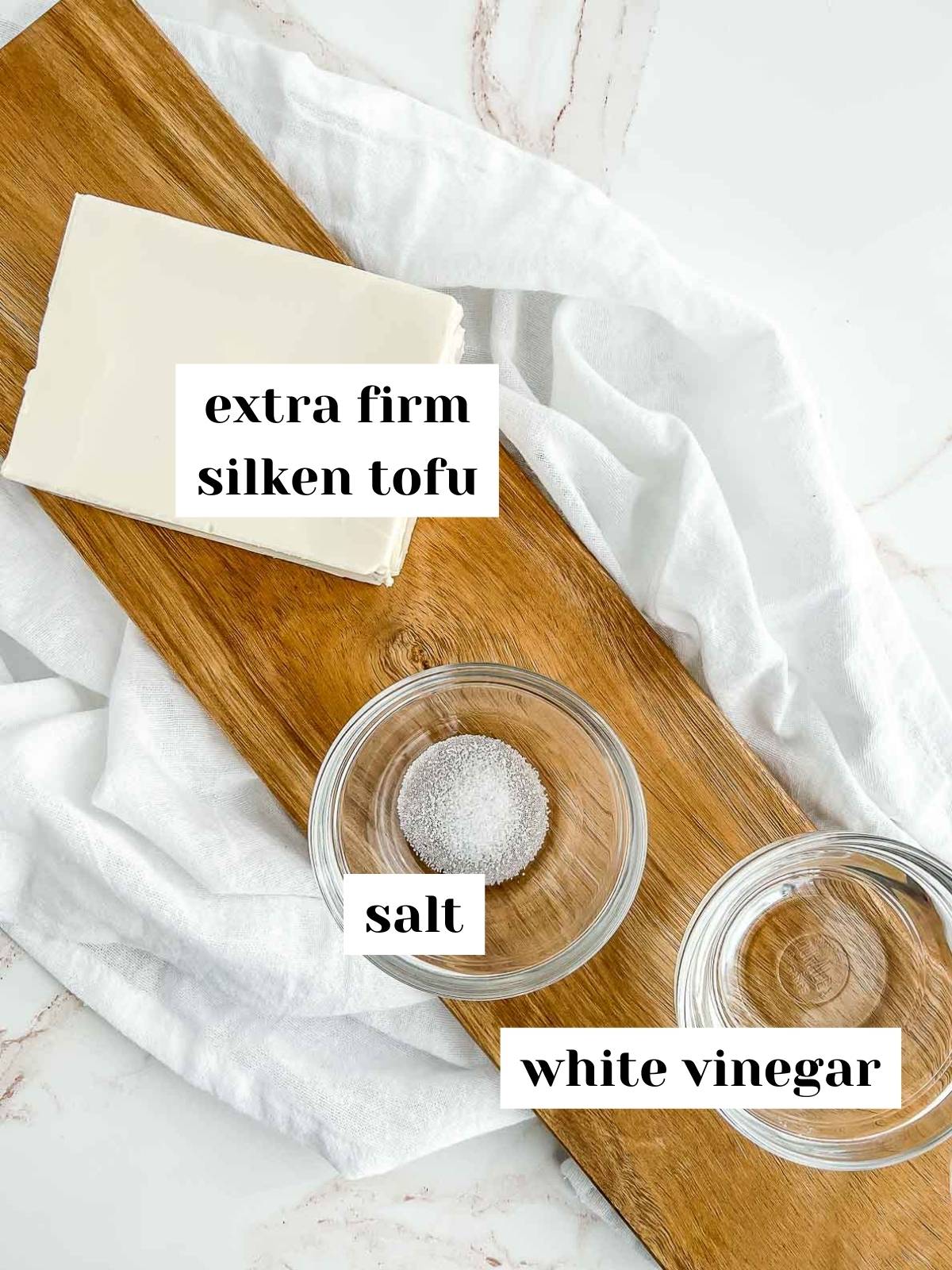 labeled ingredients including tofu, salt, and vinegar on a wood server