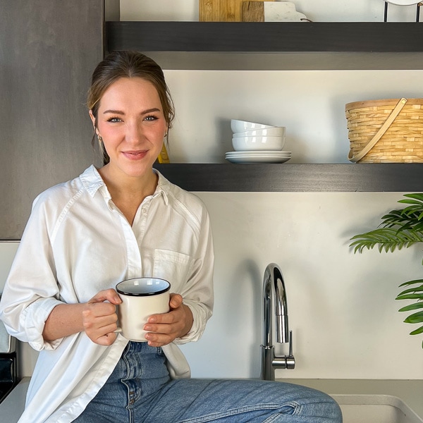 Tori, smiling and holding a mug of coffee