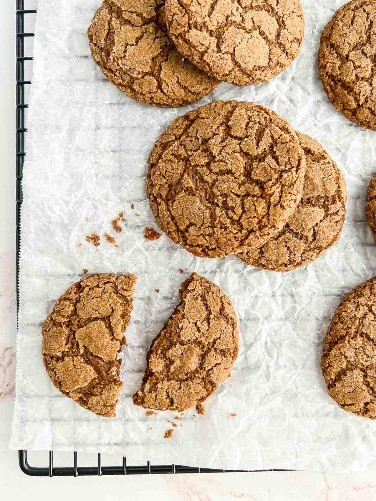 Cookies on a parchment paper-lined cooling rack with one cookie snapped in half.