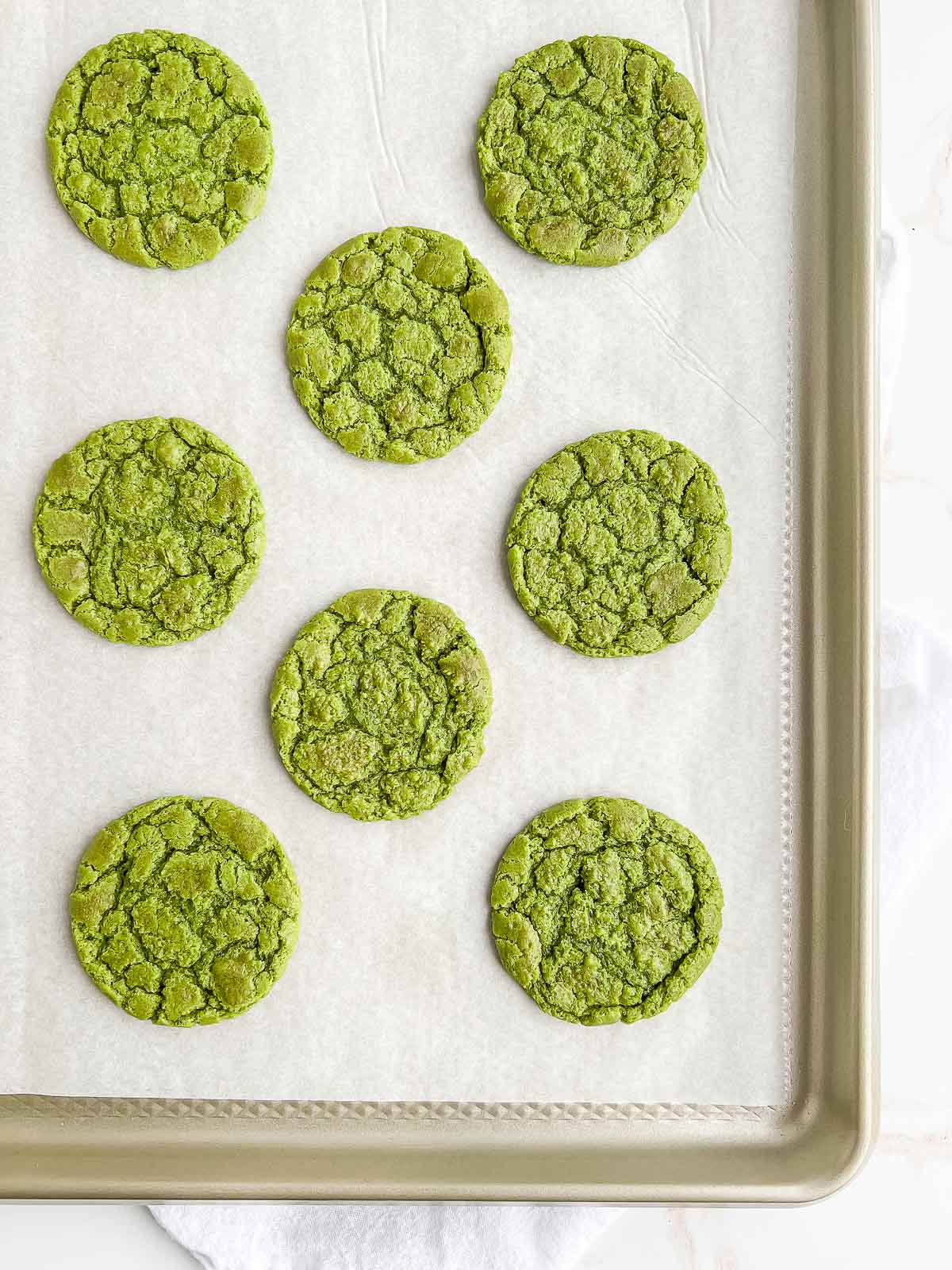 Lined baking tray of matcha cookies.