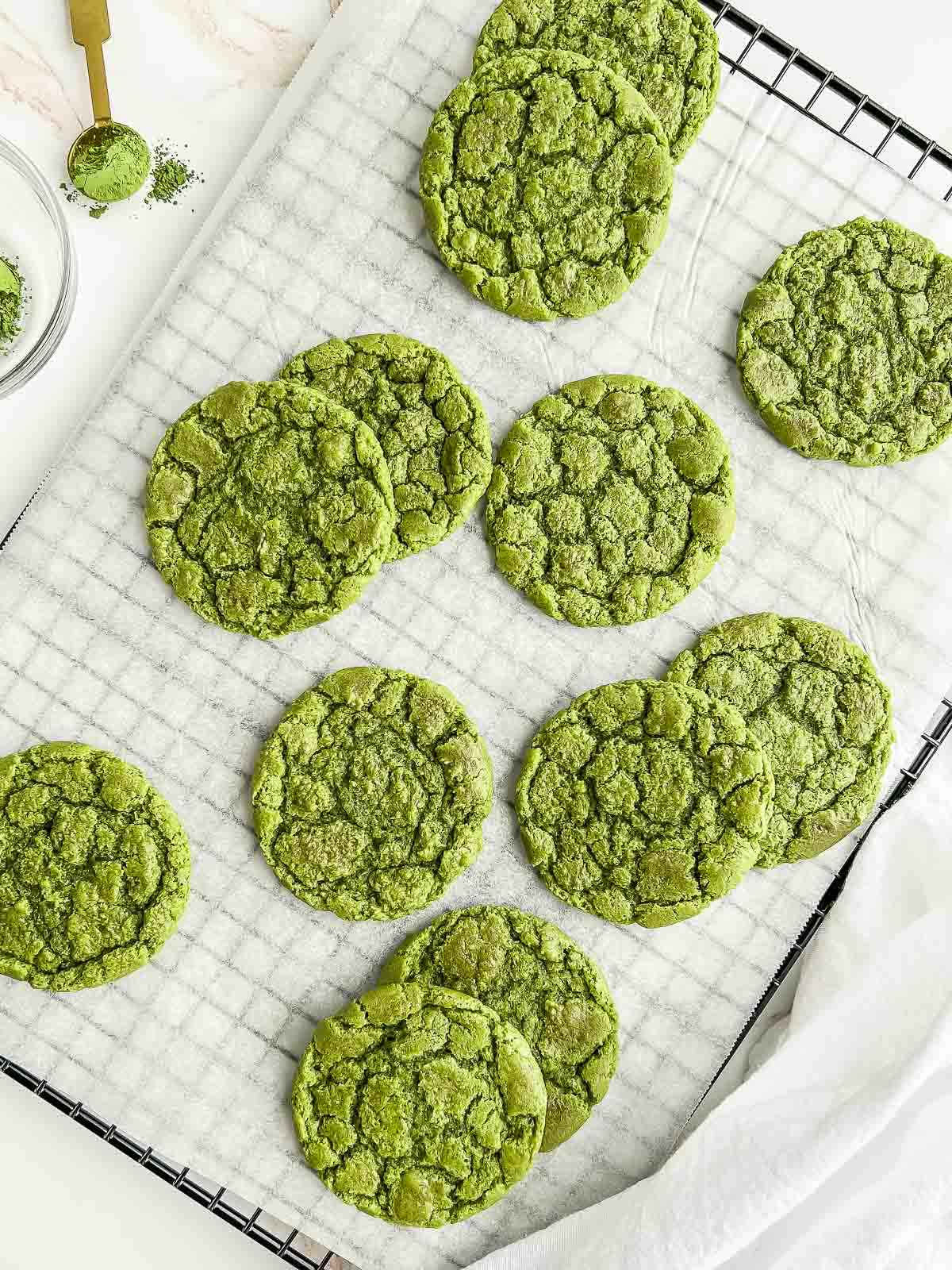Cooling tray of matcha cookies with a teaspoon of matcha powder and tea towel.