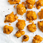 Saucy buffalo cauliflower wings strewn across some parchment paper.