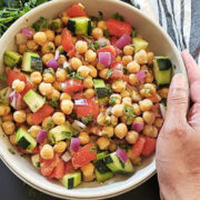 Hand placed on a bowl of chickpea salad.