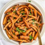Bowl of air fried parsnips topped with chopped parsley.