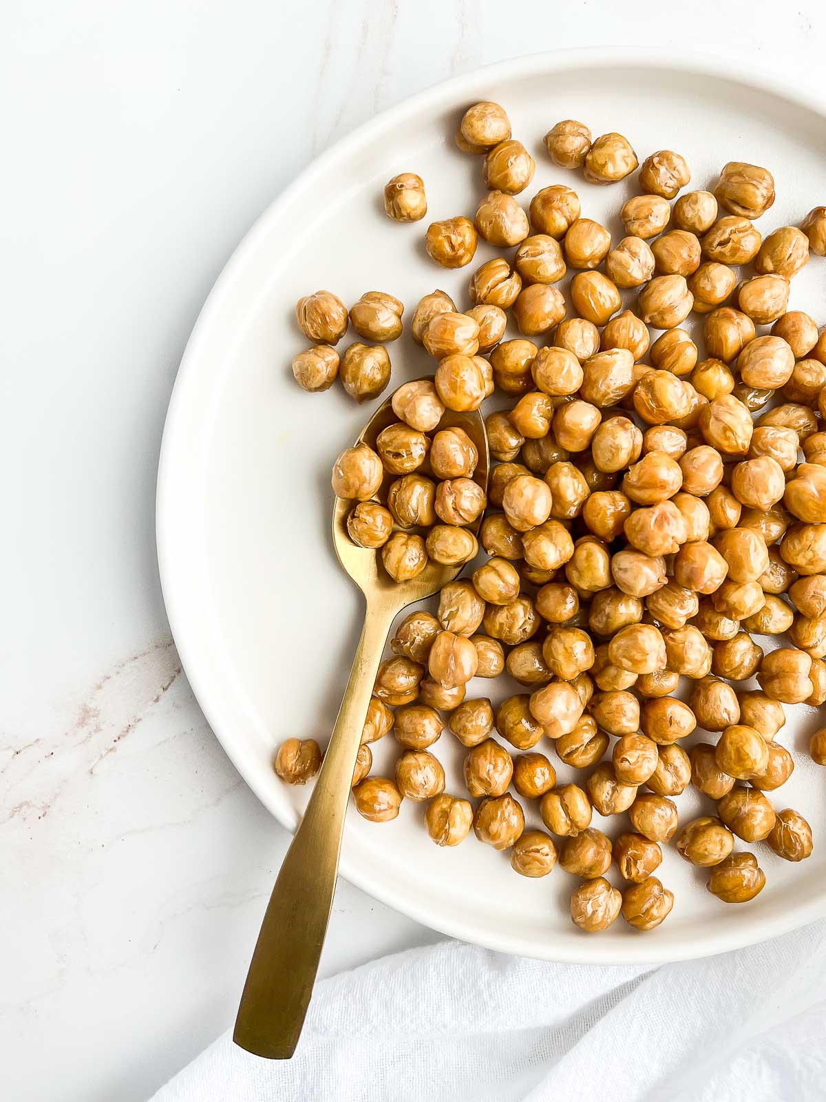 Plate of roasted chickpeas with a gold spoon.
