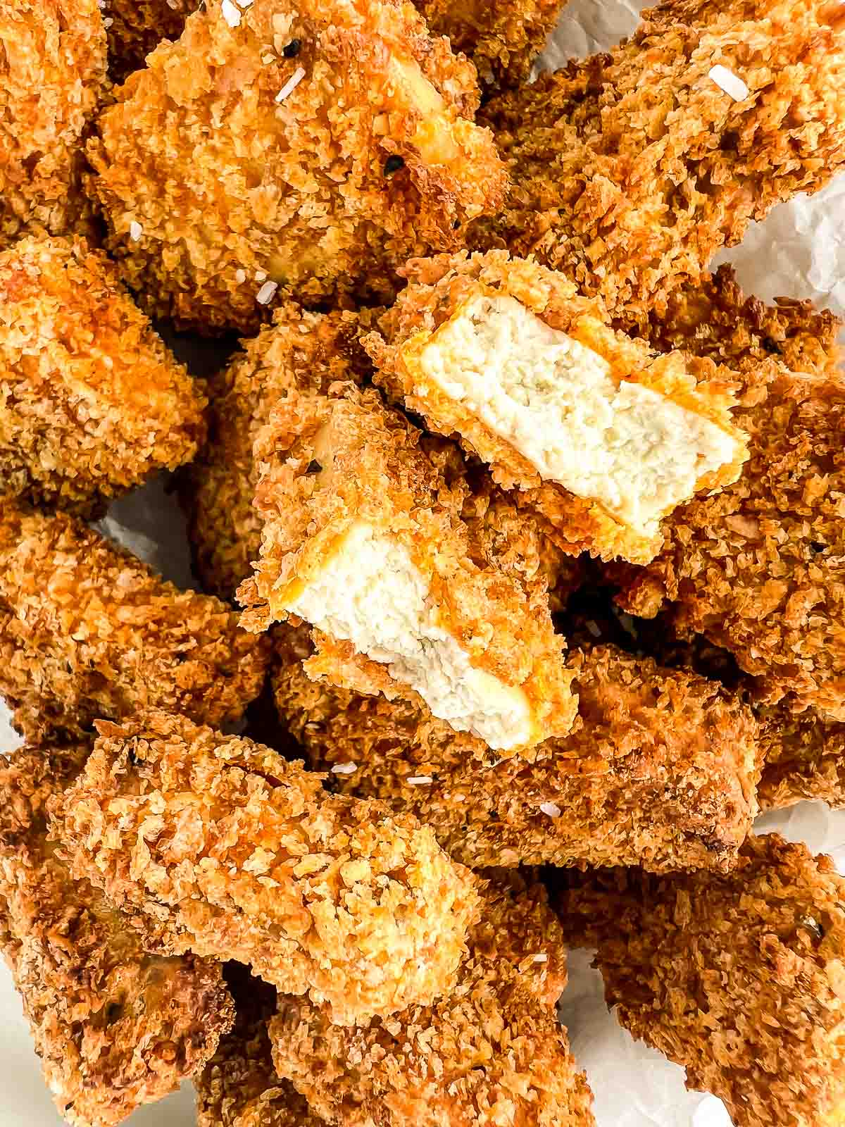 Close-up image of tofu nuggets with one nugget ripped in half.