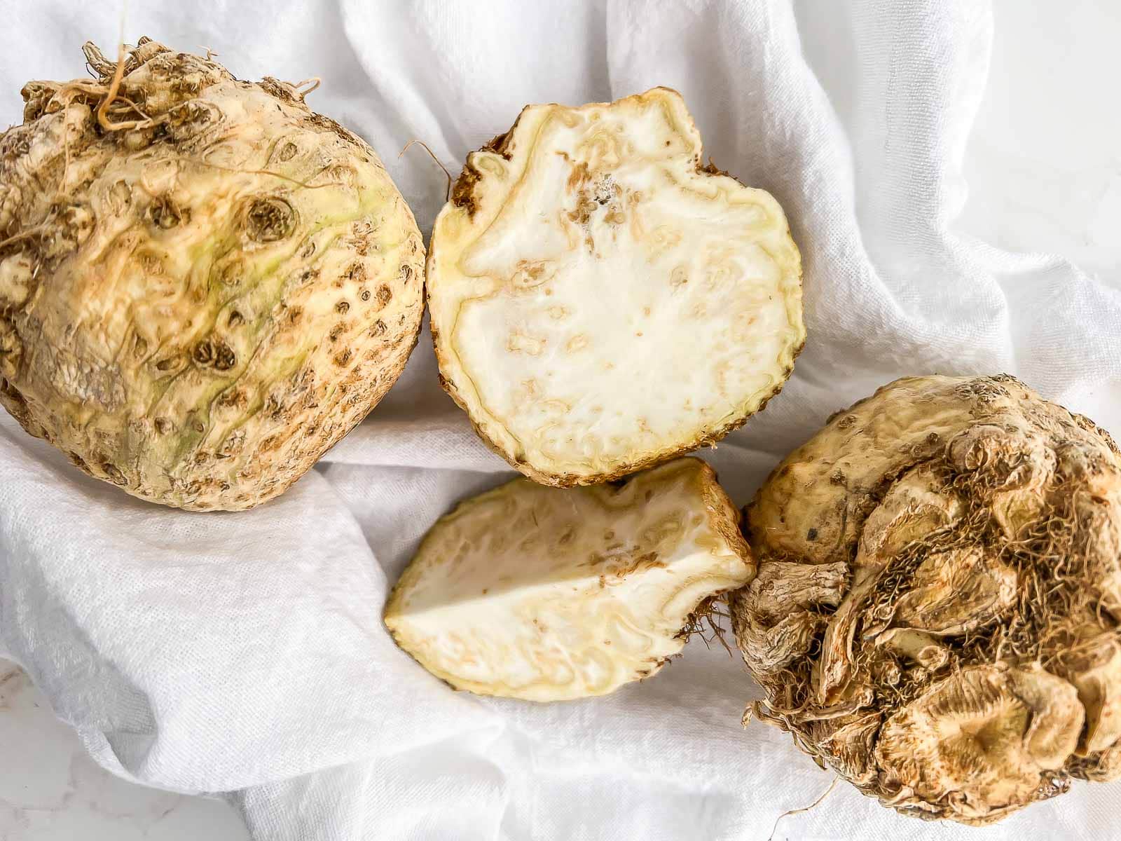 Three celery roots, with the center root sliced to show the sectional view.