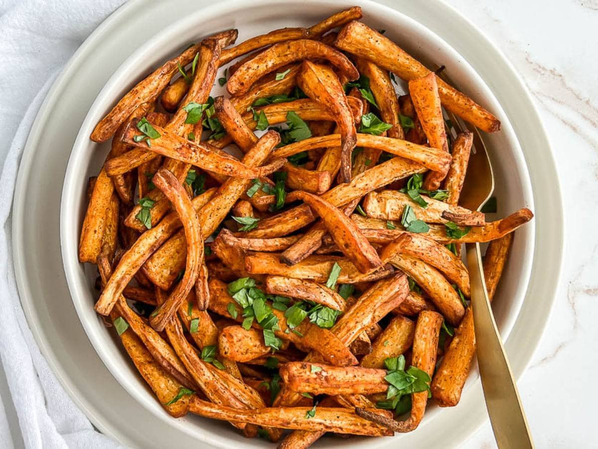 Air fried parsnips in a bowl topped with parsley.