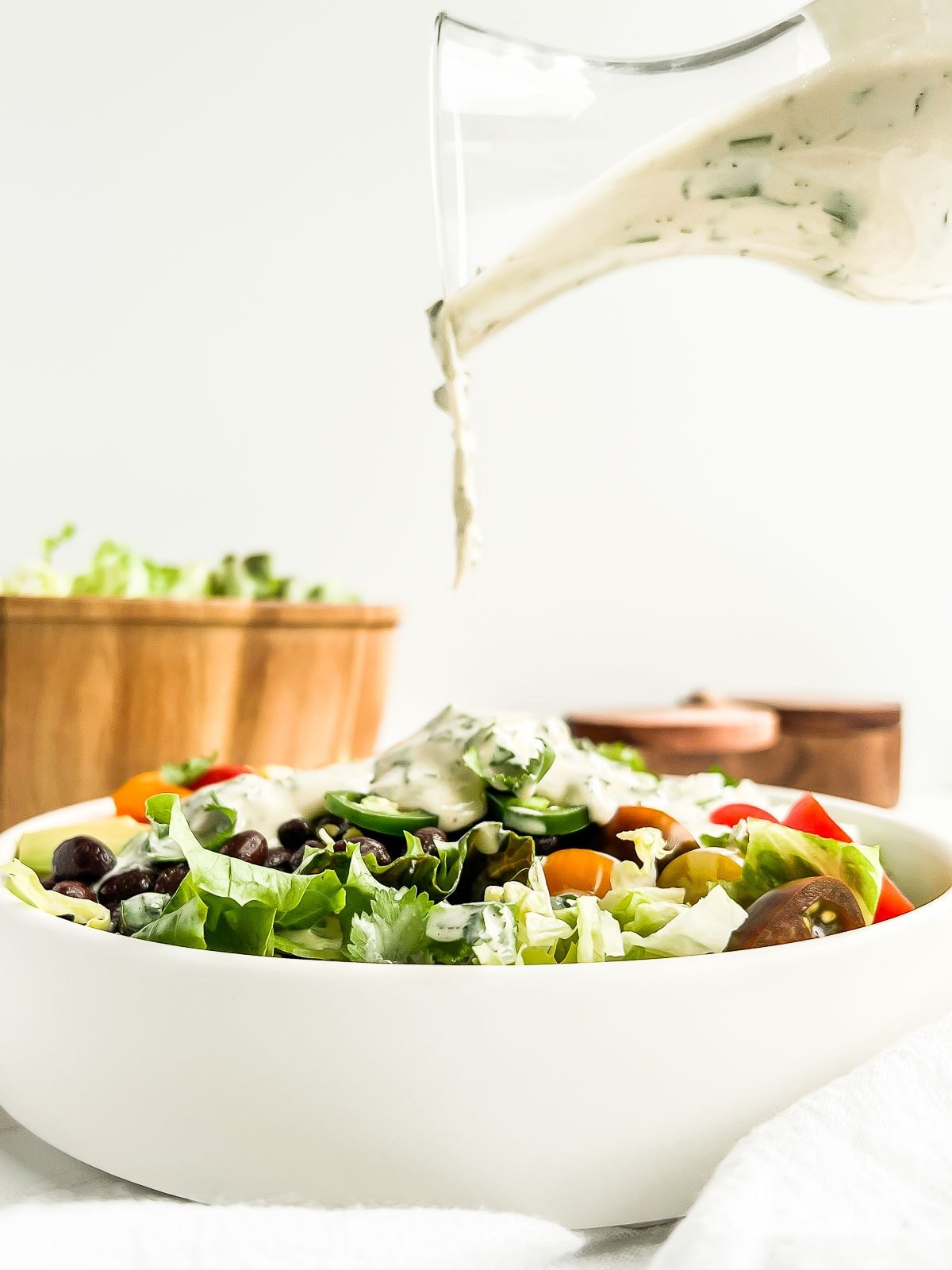 Tahini lime dressing being drizzled onto a burrito bowl.