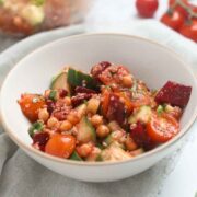 Bowl of chickpea salad with bright beets and tomatoes.