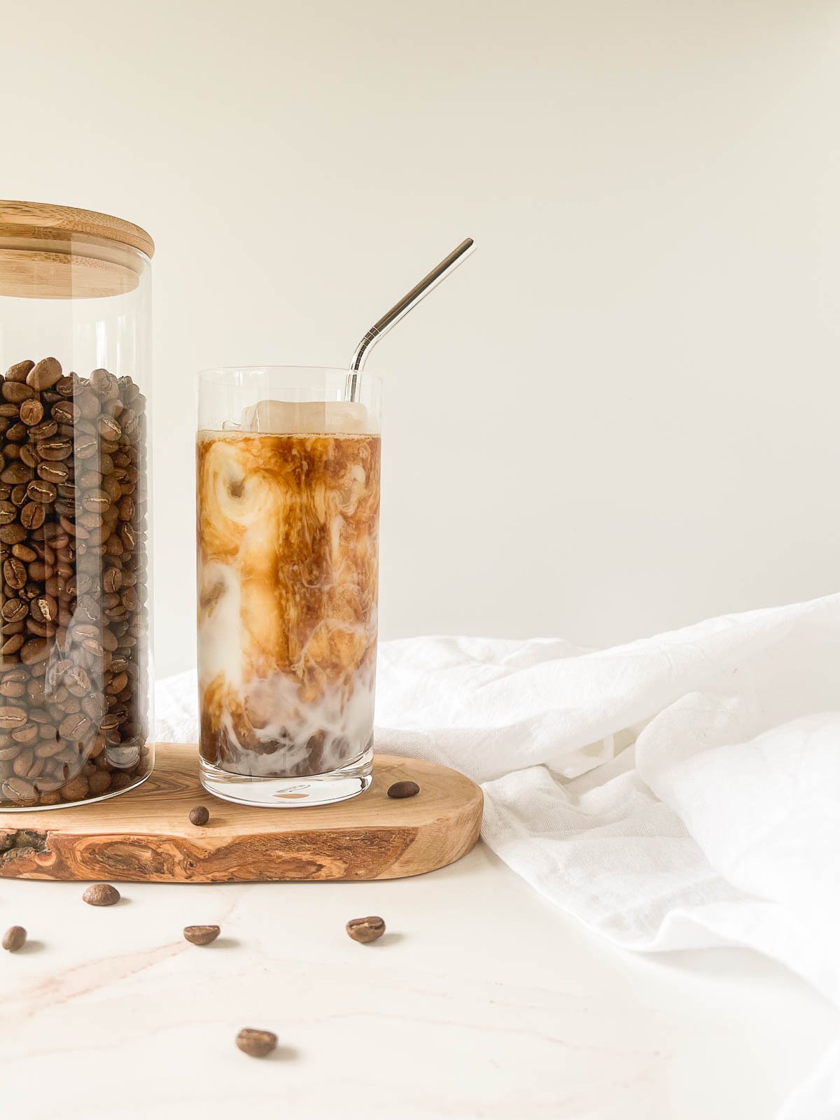 Cold brew latte on a wood board next to a jar of coffee beans.