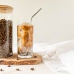 Cold brew latte on a wood board next to a jar of coffee beans.