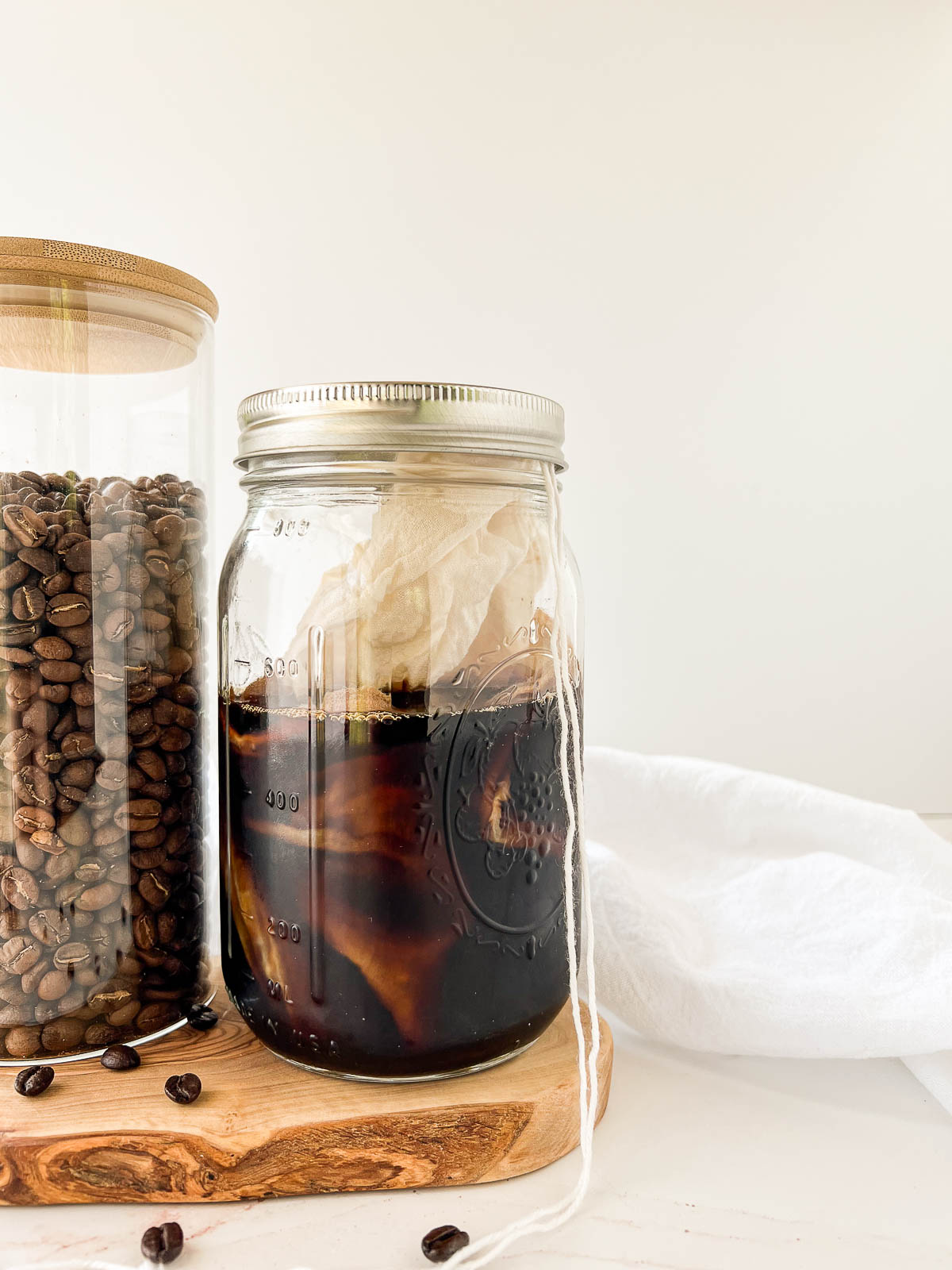 Cold brew in a mason jar with a cheesecloth filled with coarse ground coffee inside.