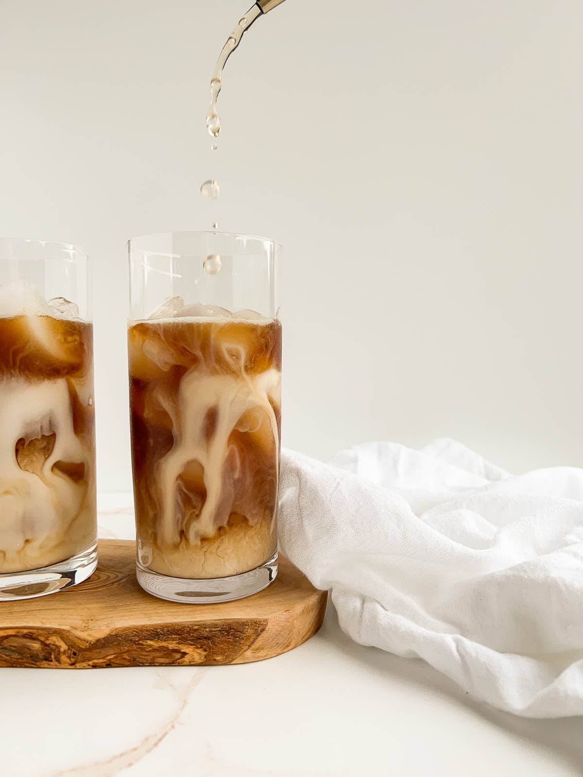 Syrup being poured into a cold brew latte with almond milk.