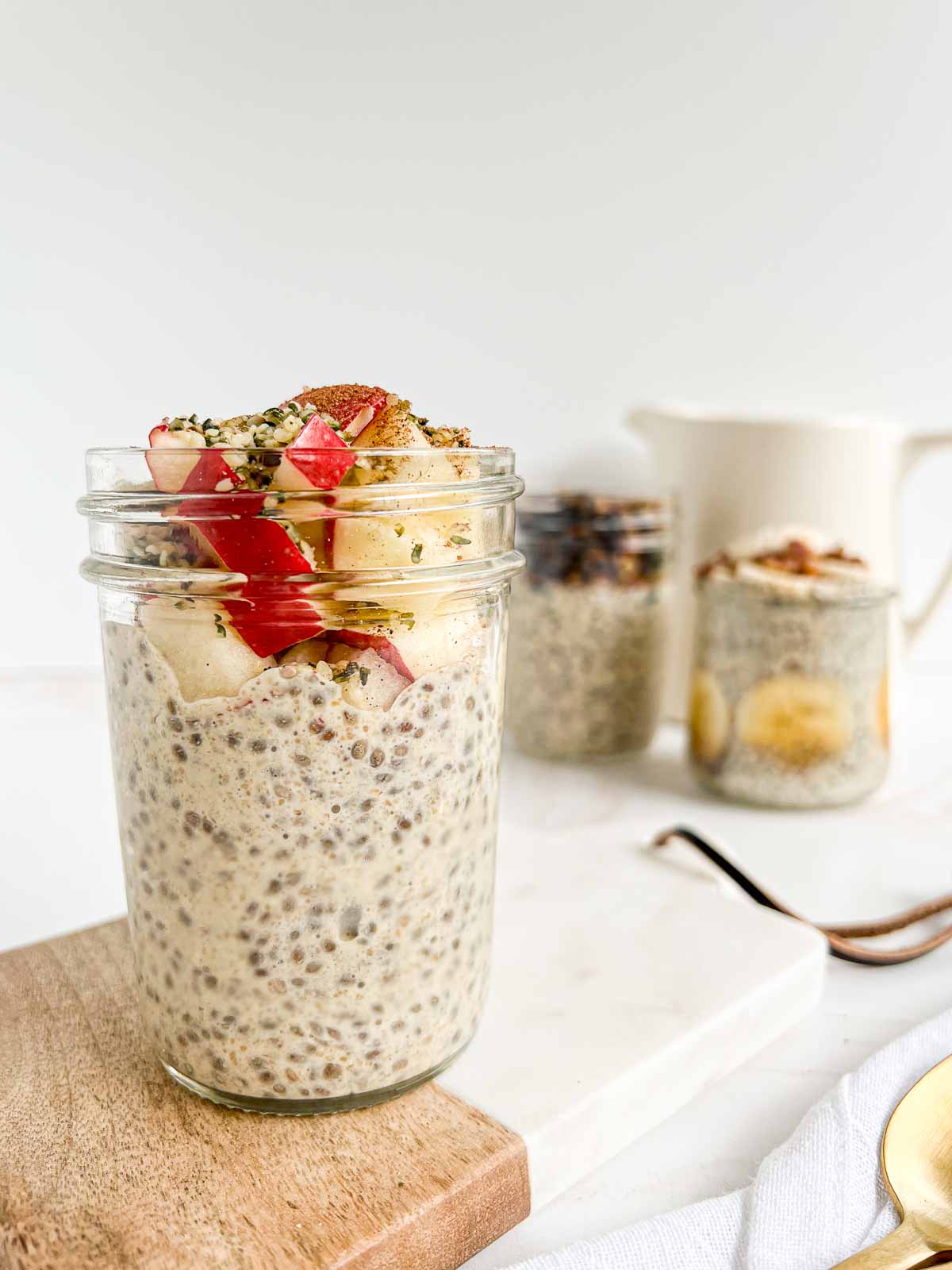 Chia pudding topped with apples, hemp hearts, and cinnamon on a serving board.