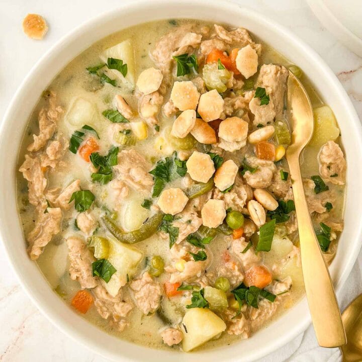 Bowl of pot pie soup with a spoon tucked in.