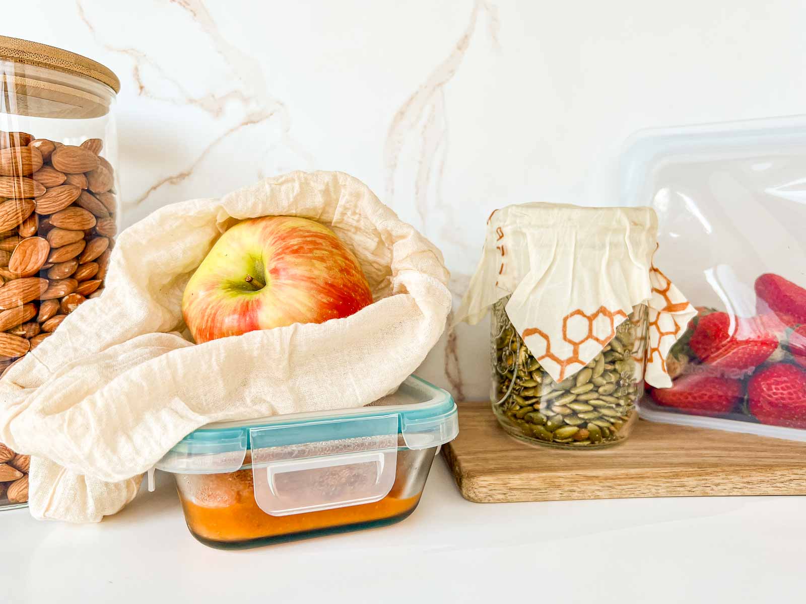 A glass jar, a glass meal prep container, a jar with wax wrap, and a Stasher bag.