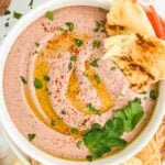 Bowl of kidney bean hummus garnished with oil, sesame seeds, and parsley.